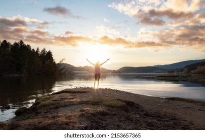 Adventurous Woman on a shore. Colorful Sunset Sky Art Render. Shoreline Trail, Port Moody, Greater Vancouver, British Columbia, Canada. Park in Modern City.