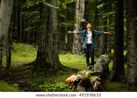 adventurous woman travels through the forest, standing with open hands and feeling the nature all around