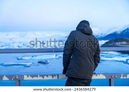 An adventurous young man on the bridge looking at Jokulsarlon lake in winter in Iceland