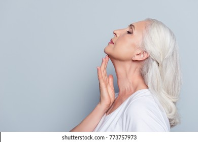 Advertisement concept. Close up profile with copy space of nice, charming, aged woman, touching her skin of neck with hand over grey background - Powered by Shutterstock