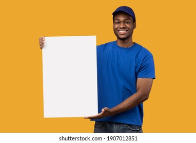 Werbekonzept. Porträt eines lächelnden afroamerikanischen Kuriers, der eine vertikale leere Tafel mit Vorlage auf orangefarbenem Studiohintergrund hält. Schwarzer Mann, der den Zustelldienst empfiehlt