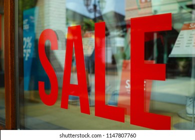 Advertising of the annual period of discounts in the store, information about sale in glass shop window with reflection of people and shopping mall - Shutterstock ID 1147807760