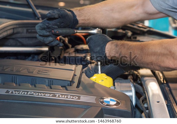 advertising car wash, Moscow, 1.11.2018: surface\
cleaning. BMW motor company badge in front of black car. German\
company. Car repair and cleaning concept - engine close-up, wiping\
parts under the\
hood
