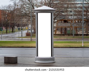 Advertising column in the city. Blank mockup for testing ad designs on the pillar next to the street. Billboard template with a white rectangle in a city. Copy space in an urban area for marketing.