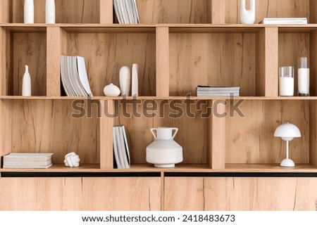 Advertising concept of home decoration and wooden furniture made for order. Part of wooden cabinet fill with books and decor. Bookshelf with magazines in living room