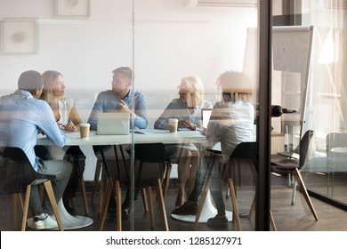 Advertising department brainstorming at modern office boardroom behind closed doors, view through the glass wall. Diverse staff led by ceo discussing new project sharing ideas thoughts and sales pitch - Shutterstock ID 1285127971