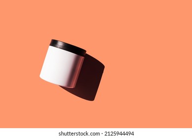 Advertising isolated container on bright sunny pink background. Skincare, bodycare beauty product in plastic pot package concept. White unbranded, balsam, face or hand creme jar mockup