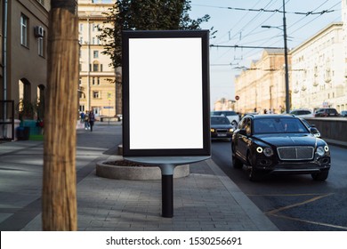 Advertising And Marketing Means In Urban Area. Billboard With Blank Digital Screen Standing By Busy Road In City Center. Pedestrians Passing Banner By, Drivers Riding In Cars, Passengers At Bus Stops