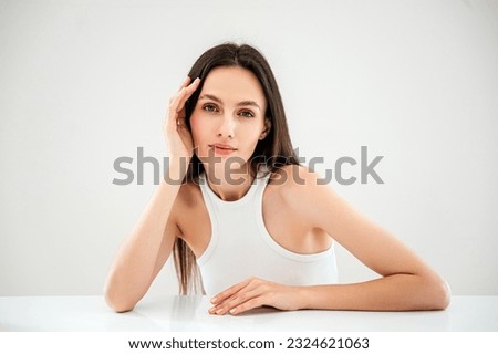 advertising of skincare and bodycare concept. studio shot of young woman with healthy radiant skin looking at camera, hold hand near face, standing isolated against copy paste grey background