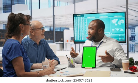 Adviser shows green screen on a tablet to middle aged people in modern office, meeting to discuss retirement and pension plan. Financial expert broker helping senior couple with finances. Camera B. - Powered by Shutterstock