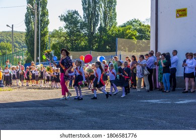 Adygea, Russia - September 1, 2020: A Happy Smiling Teacher With A Bouquet Of Flowers Walks With First Graders In The School Yard On The Day Of Knowledge