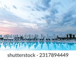 Aegean sea sunrise behind pool, umbrellas and sun deck chairs at Kallithea, Greece