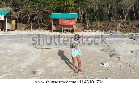 Aereal drone view of young pretty brunette woman relaxing and drinks coconut water and walking on the ocean beach under blue sky in sunny day. Seascape view