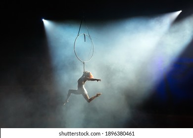 Aerial acrobat in the ring. A young girl performs the acrobatic elements in the air ring