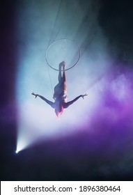 Aerial acrobat in the ring. A young girl performs the acrobatic elements in the air ring