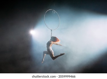 Aerial acrobat in the ring. A young girl performs the acrobatic elements in the air ring