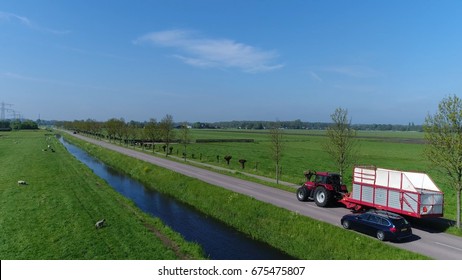 Aerial Agricultural Photo Of Side Of Tractor Pulling A Loader Wagon For Picking Up Animal Fodder Dried Grass Tractor Then Is Caught Up By Station Wagon Vehicle Beautiful Day Blue Sky