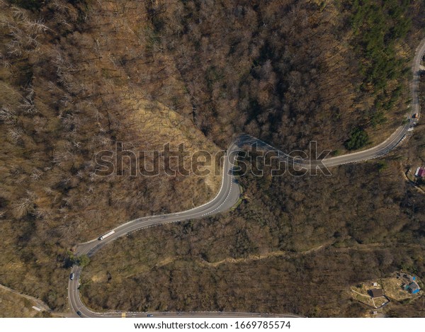 Aerial autumn road from above view of cars on a\
zig zag road. Season forest road landscape. Mountain forest road in\
autumn.