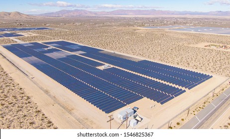 AERIAL: Barren Landscape Surrounds A Large Farm Of Solar Panels In California. Flying Above Long Rows Of Photovoltaic Panels Installed In A Remote Part Of United States. Solar Cells In The Desert.