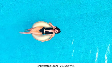 Aerial. Beautiful Young Woman Swims In The Pool On Inflatable Ring. Top View From Drone.