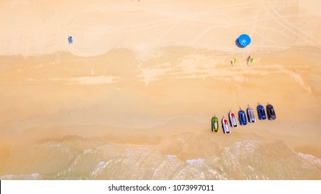 Aerial : Bird Eye View Of Sea Waves  Against The Sand Beach Coast Line And Overhead View Of A Water Scooter Rental Point Under Blue Umbrella