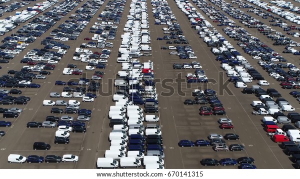 Aerial bird view above car lot with rows\
of vehicles ready for\
transportation