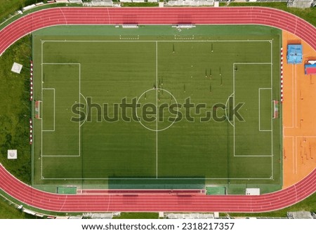 Aerial bird view from above of sport center field for game of soccer with players running on green grass