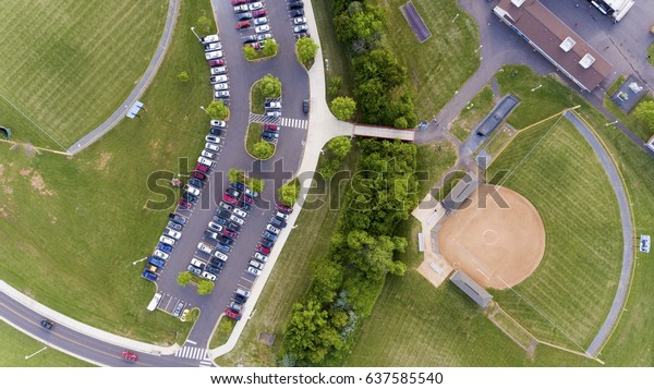Aerial Birds eye view of baseball field with cars in\
parking lot