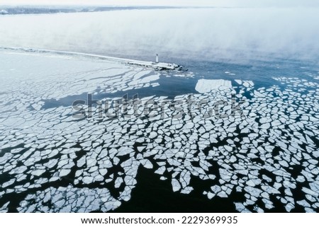 Aerial birds eye view of frozen River Daugava entering Baltic sea, winter sunrise