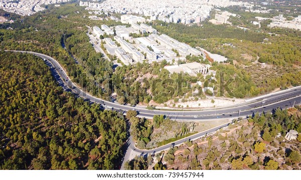Aerial bird\'s eye view of highway passing through\
forest with snake like\
shape