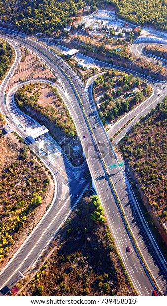 Aerial bird\'s eye view of highway passing through\
forest with snake like\
shape