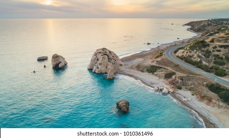 Aerial Bird's eye view of Petra tou Romiou, aka Aphrodite's rock a famous tourist travel destination landmark in Paphos, Cyprus. The sea bay of goddess Afroditi birthplace at sunset from above. 