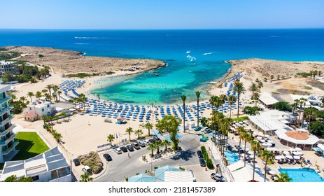 Aerial bird's eye view of Vathia Gonia beach, Ayia Napa, Famagusta, Cyprus.  Landmark tourist attraction rocky bay with golden sand, sunbeds, sea restaurants in Agia Napa on summer holidays from above