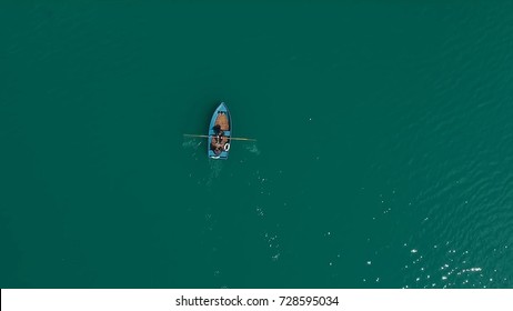 Aerial Boat On The Lake. Aerial View On Two Men In A Boat On A Lake, Rowed To The Shore. Lonely Boat In The Middle Of The River, Lake. Boat Single Row On Sea With Reflection In The Water In The