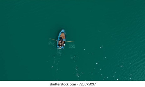 Aerial Boat On The Lake. Aerial View On Two Men In A Boat On A Lake, Rowed To The Shore. Lonely Boat In The Middle Of The River, Lake. Boat Single Row On Sea With Reflection In The Water In The