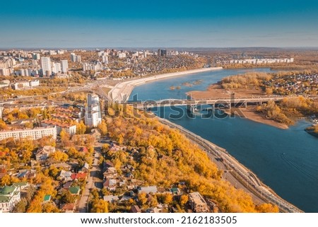 Aerial cityscape view of city districts with automobile bridge over river in Ufa. Autumn parks with colorful trees