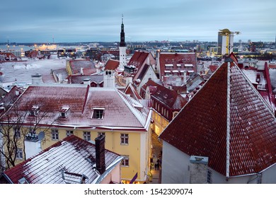 Aerial Cityscape View Of Tallinn Old Town In Winter Day. Red Rooftops From Tiles, Golden Cockerel Weathervane, Church Spire, Modern Skyscrapers And Sea Far Away.