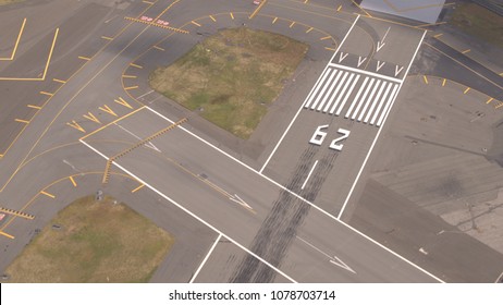 AERIAL, CLOSE UP: Flying Close Above Large Asphalt And Concrete Piste On Big Modern International Airport Near Busy Turnpike Highway. Runway Designator Markings, Numbering And Signs On The Track