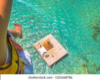 Aerial Closeup View Of A Woman Parasailing. Below, The Landing Platform On The Spectacular Blue Sea Of Deer Island, East Coast Of Mauritius, Indian Ocean.