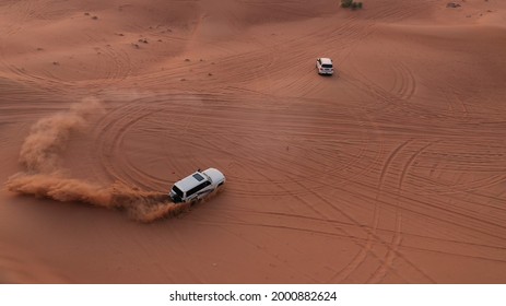 AERIAL. Column of white cars travelling in sand desert.