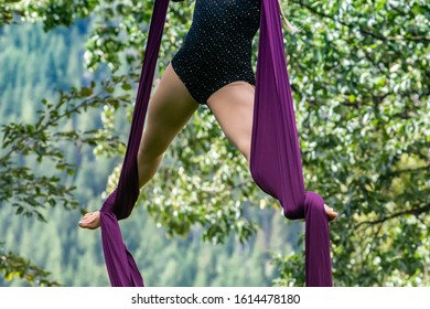 An Aerial Contortionist Is Seen With Silk Ribbons Wrapped Around Feet During An Outdoor Dance Performance In Nature, With Copy Space To Both Sides