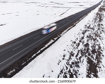 Aerial Diagonal View Of A Road With One Lane And Snow In Winter With A Bus And Motion Blur