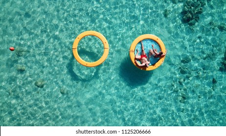 Aerial drone bird's eye top view of couple sitting in inflatable pools and matress in rocky emerlad water tropical caribbean resort - Powered by Shutterstock