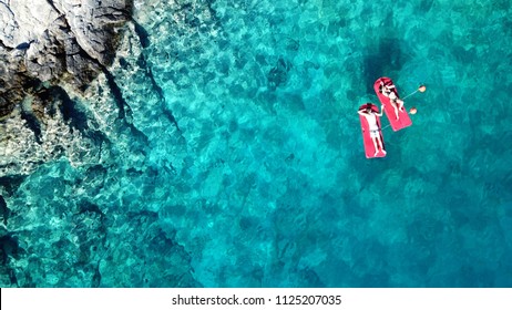 Aerial drone bird's eye top view of couple sitting in inflatable matress in rocky emerald water tropical caribbean resort - Powered by Shutterstock