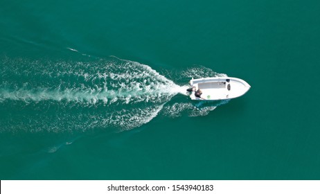 Aerial drone bird's eye top view photo of small motor boat cruising in emerald clear water lake - Powered by Shutterstock