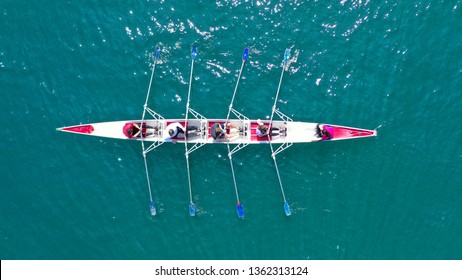 Aerial drone bird's eye view photo of red sport canoe operated by team of young men and women in emerald clear sea - Powered by Shutterstock