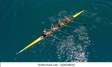 Aerial drone bird's eye view of yellow sport canoe operated by team of young women in deep blue sea waters - Powered by Shutterstock