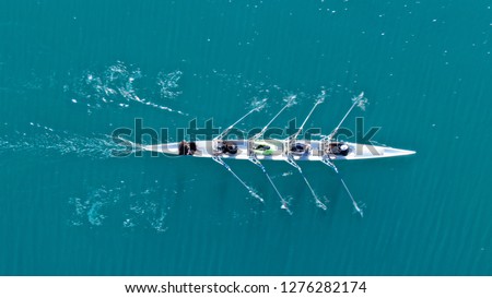 Aerial drone bird's eye view of sport canoe operated by team of young women in turquoise clear waters