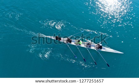 Aerial drone bird's eye view of sport canoe operated by team of young men in emerald clear sea