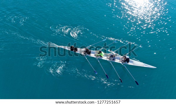 Aerial drone bird\'s eye view of\
sport canoe operated by team of young men in emerald clear\
sea